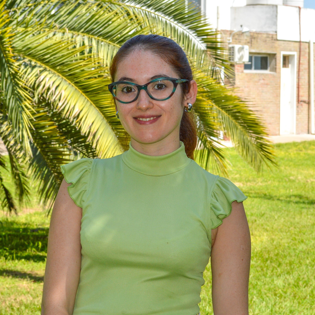 Bioingeniera Camila Duré. Foto de frente. Mujer ronriendo. Pero largo rojizo. Con lentes.