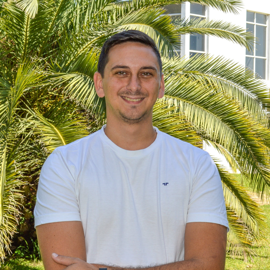Licenciado Lucas Dorsch. Foto de frente. Hombre sonriendo. Pero corto rubio. Barba corta. Fondo verde de vegetación.