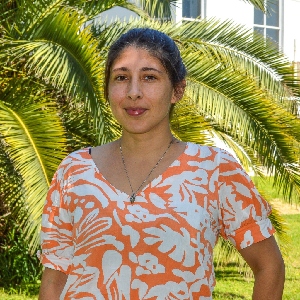 Bioingeniera Solange Milessi. Foto de frente. Mujer de pelo largo castaño. Fondo verde de vegetación.